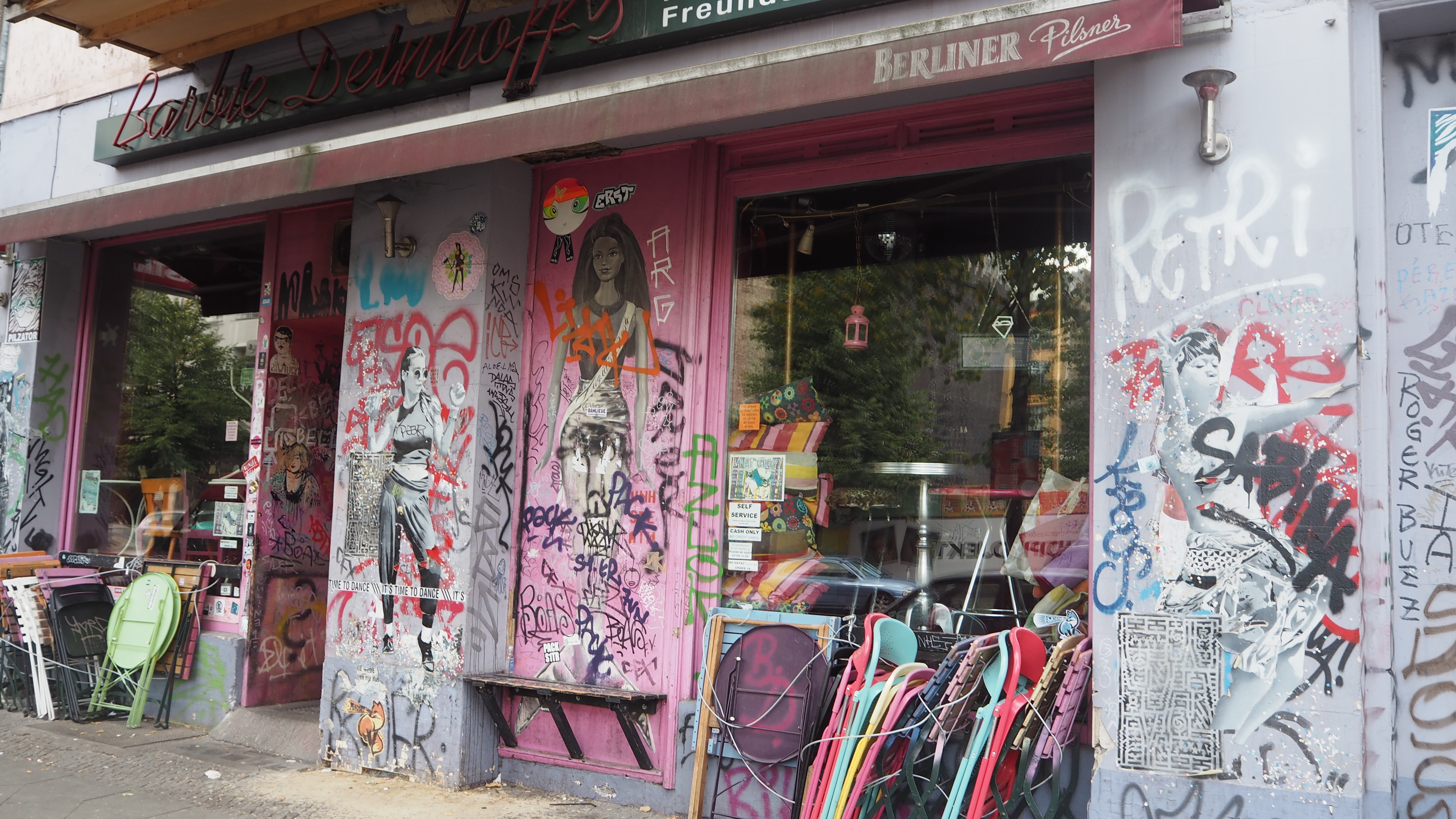 A pink cafe covered in street art, with black and white women painted on the walls 