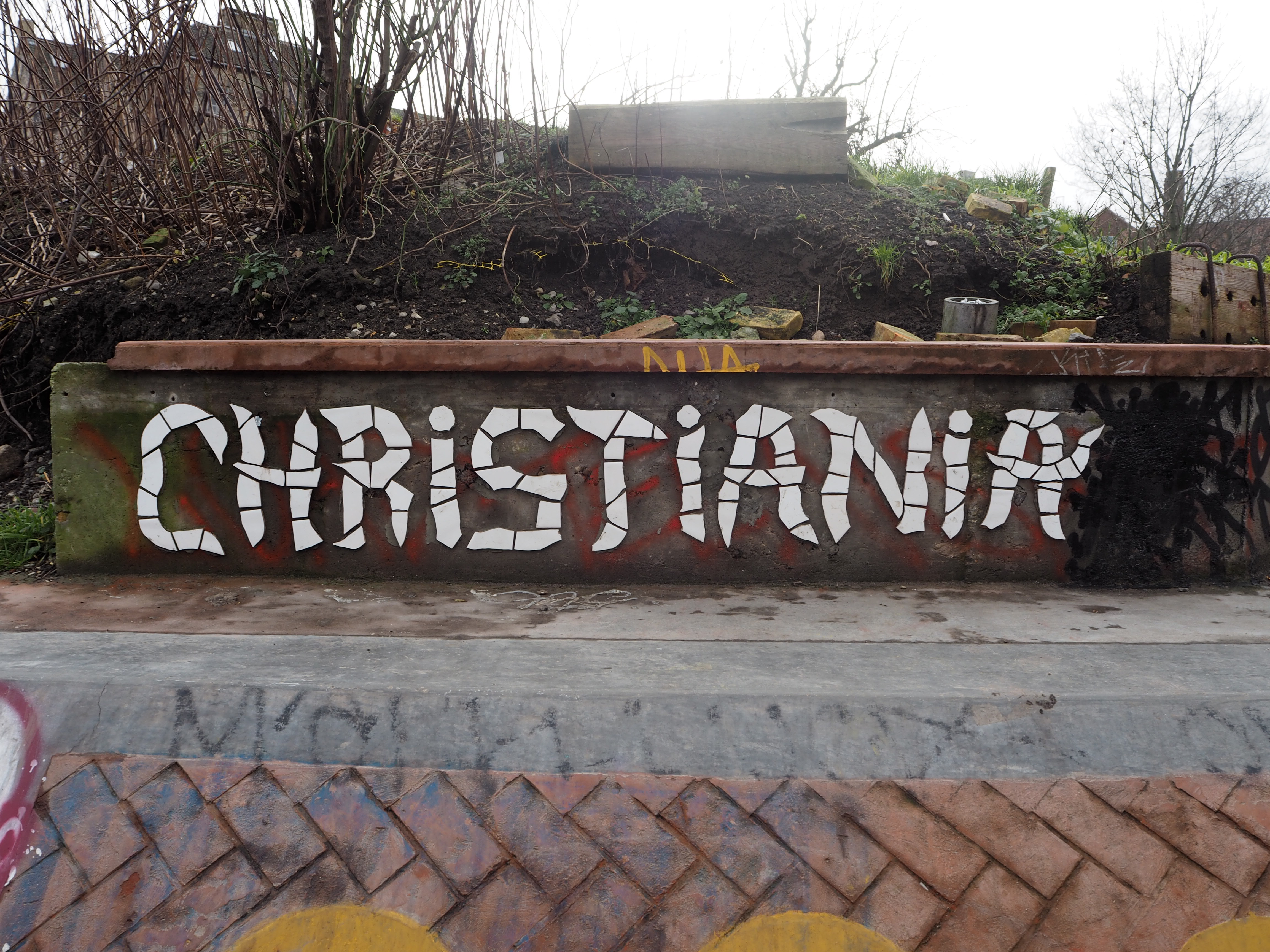 A metal wall with the word Christiana in white mosaic patterns, in Freetown Christiana Copenhagen
