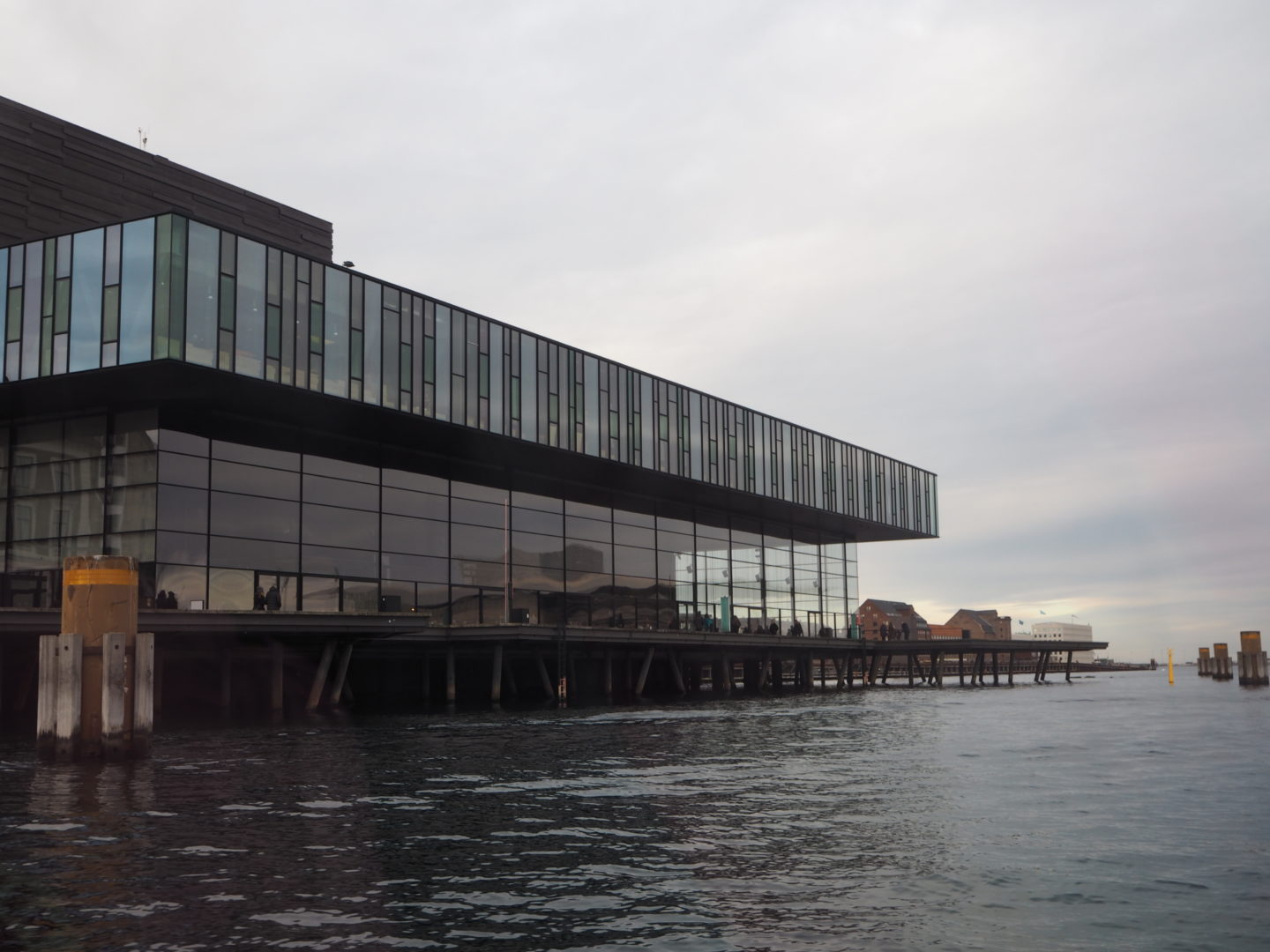 A large glass building with a flat roof overlooks the river