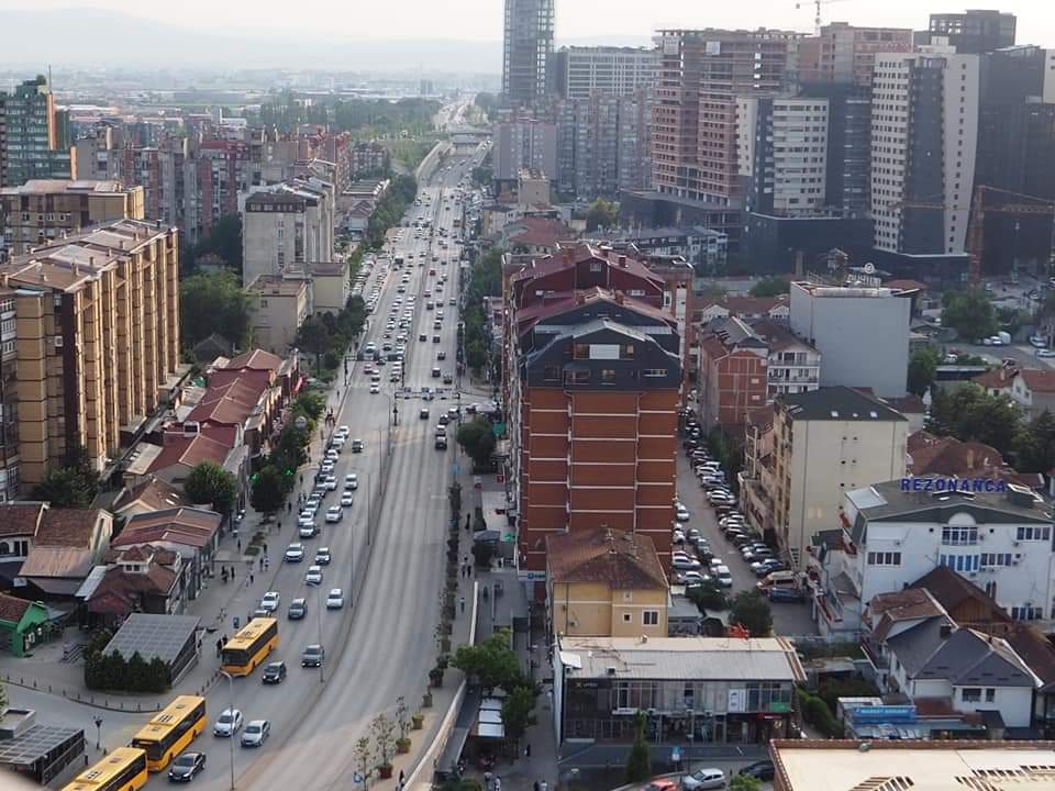 Aerial view of yellow buses driving along the road in Pristina, Kosovo. If you're visiting Pristina, you'll see a lot of these buses